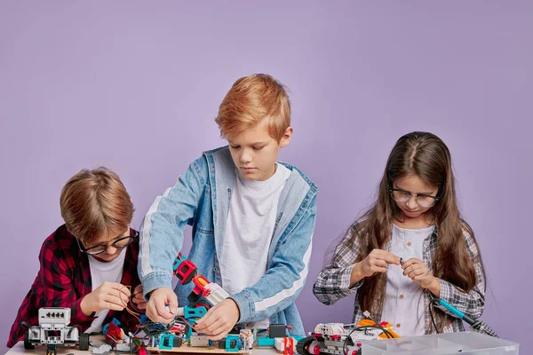 Entusiastas crianças preocupadas montando robôs de tecnologia, futuros engenheiros — Fotografia de Stock