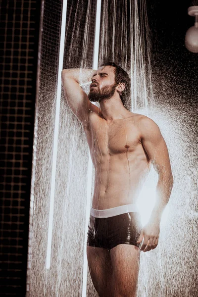 Hombre musculoso fuerte bajo el agua corriente — Foto de Stock