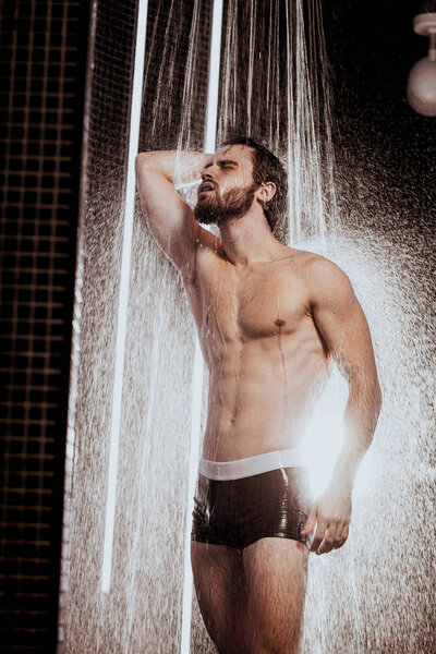 Сильный мускулистый человек под проточной водой