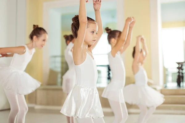 Grupo de pequeñas bailarinas caucásicas de pie en fila y practicar ballet —  Fotos de Stock