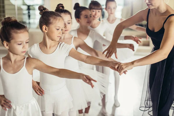 Attractive slim ballerina in black tutu skirt show right poses in ballet to kids — Stock Photo, Image