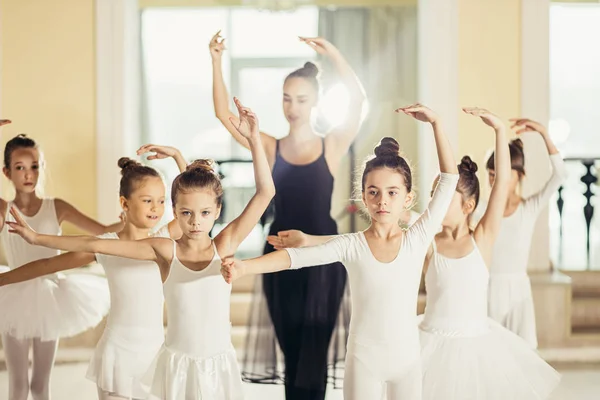 Ung kvinnlig ballerina show rätt posera för barn i studio — Stockfoto