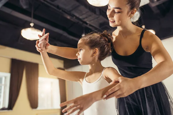 Pretty woman ballet dancer practicing with little girl — Stock Photo, Image