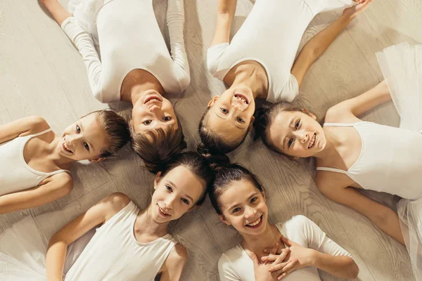 Uśmiechnięte małe dziewczynki baleriny leżące na podłodze w kółku — Zdjęcie stockowe