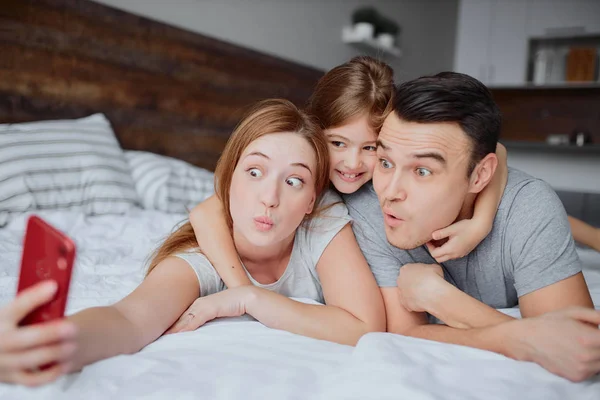 Grappig gezin met kind op bed — Stockfoto