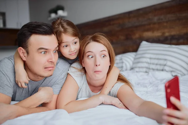 침대에 누워 있는 감정적 백인 가족의 여가 시간 — 스톡 사진