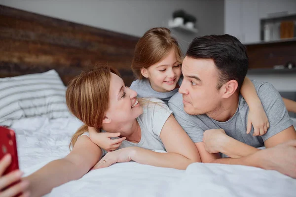Συναισθηματική ευτυχισμένη οικογένεια με την κόρη στο κρεβάτι — Φωτογραφία Αρχείου