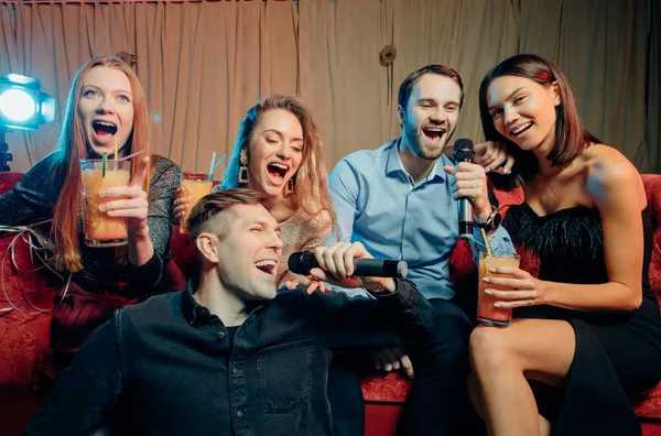 Alegres amigos felizes se divertir e cantar na festa de karaoke no clube noturno — Fotografia de Stock