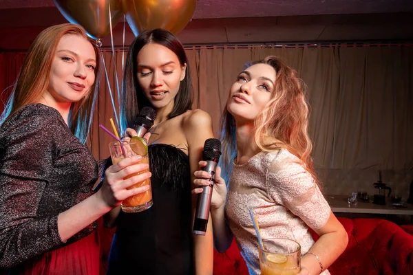 Portrait de femmes caucasiennes heureuses chantant au micro dans un bar karaoké — Photo
