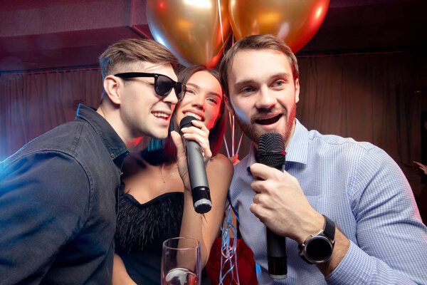 Портрет счастливых кавказцев, поющих на микрофоне в караоке-баре

