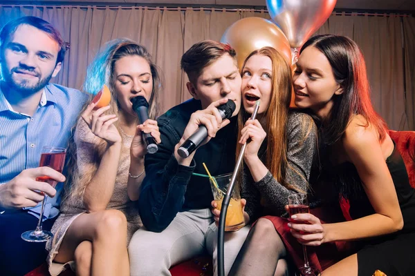 Groep jonge vrienden in karaoke bar — Stockfoto