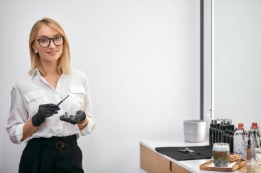 Dost canlısı gülümseyen güzellik uzmanı iş yerinde kameraya bakıyor.