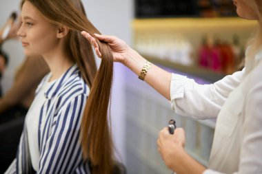 Dikkat et kuaför müşterilerin saçlarını elinde tutuyor.