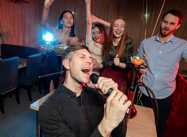 Happy young singers in karaoke bar — Stock Photo, Image