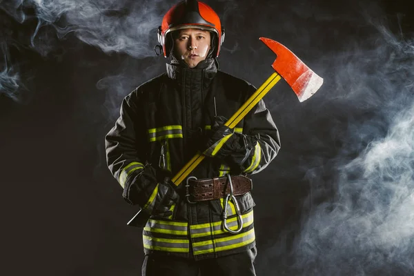 Poważny i pewny siebie strażak w zadymionym tle — Zdjęcie stockowe