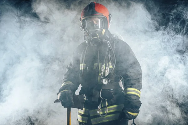 Brandbekämpningskoncept. ung man brandman i rökig bakgrund — Stockfoto