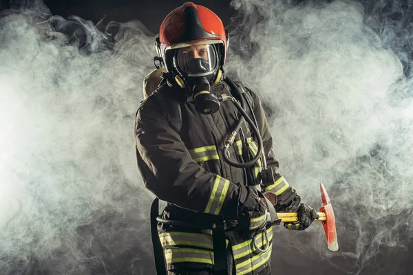 Bombero serio y confiado en el fondo ahumado —  Fotos de Stock