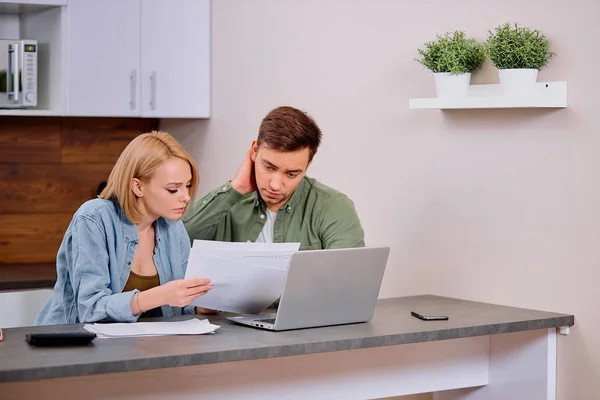 Bezorgde getrouwde man en vrouw zitten samen aan tafel met laptop — Stockfoto