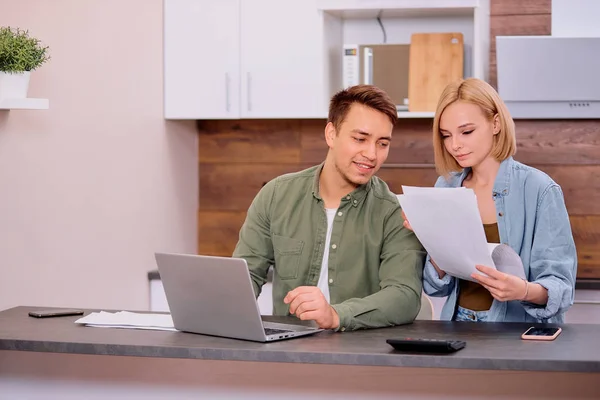 Jong gelukkig paar zitten met documenten bespreken over contant geld rekeningen in de huiskeuken — Stockfoto