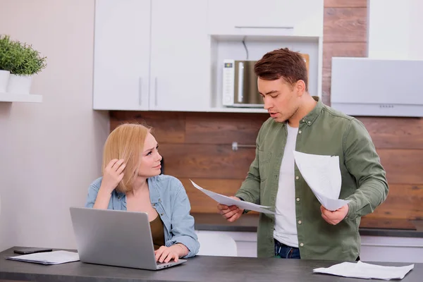 Jonge Kaukasische echtgenoten zitten met laptop en documenten thuis — Stockfoto