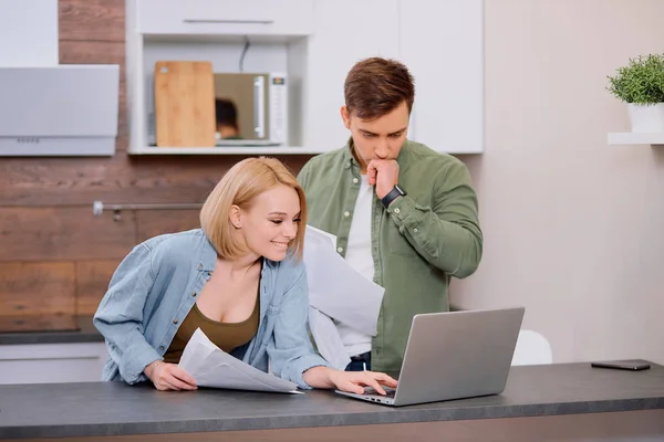 Щаслива подружня пара використовує ноутбук вдома під час домашнього аудиту — стокове фото