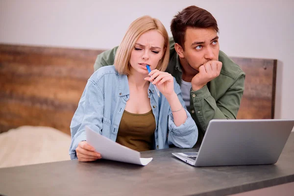 Puzzled married man and woman sitting together at table with laptop — Stock Photo, Image