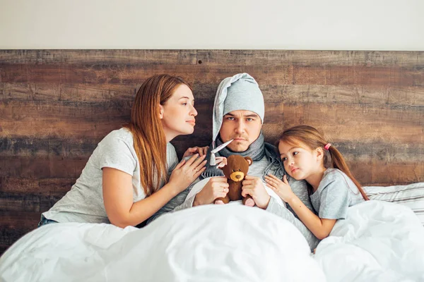 Nemocná rodina doma spolu leží na posteli — Stock fotografie