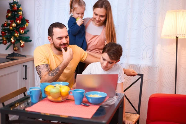 Jonge ouders met kinderen zitten samen in de keuken — Stockfoto