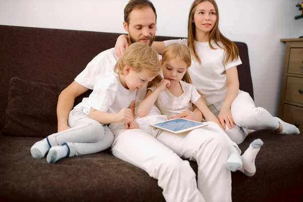 캅카스 가족은 집에서 소파에 앉아 타블렛을 사용 한다 — 스톡 사진