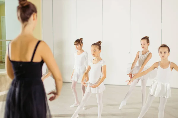 Молодая балерина показывает правильную позу для детей в студии — стоковое фото