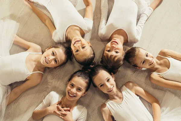 top view on little girls ballerinas lying on floor in circle