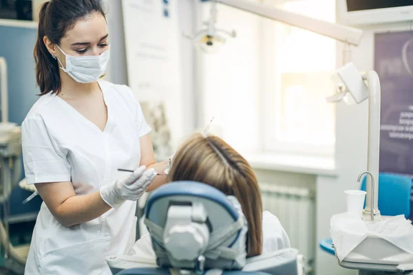 Voorzichtige professionele tandarts vrouw behandeling van tanden — Stockfoto