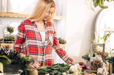 Mutlu kadın çiçekçi çiçeklerle çalışmaktan zevk alıyor.