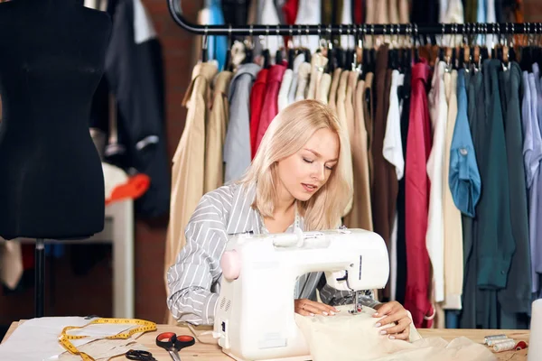 Fair-haired attractive seamstress concentrated on sewing at workplace — 스톡 사진