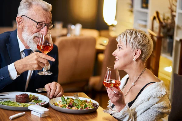 세련 된 노인 부부 가 식당에서 전자 담배를 사용하며 식사를 하고 있다. 이코스 — 스톡 사진