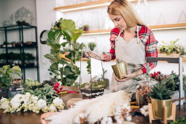 Çiçek besteleyen kadın, çiçeklerle çalışmaktan zevk alıyor.