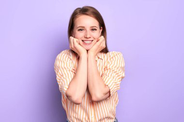 Studio shot of young pretty girl smiling happily, gazing in camera