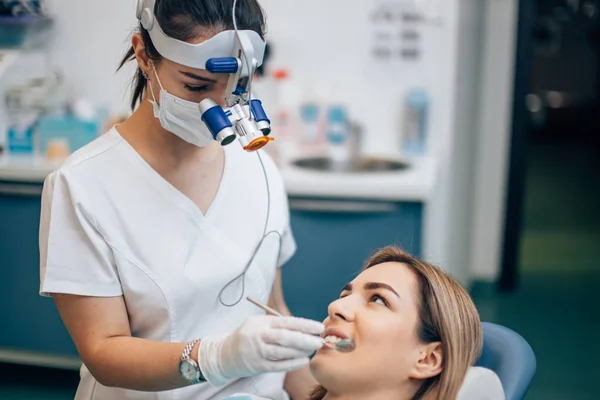 Voorzichtige vrouwelijke tandarts in tandartspraktijk — Stockfoto