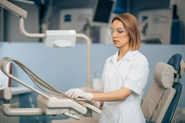 Allvarlig tandläkare kvinna som använder medicinsk utrustning på jobbet — Stockfoto
