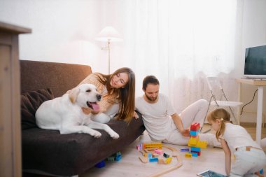 children playing together on floor while young parents relaxing at home