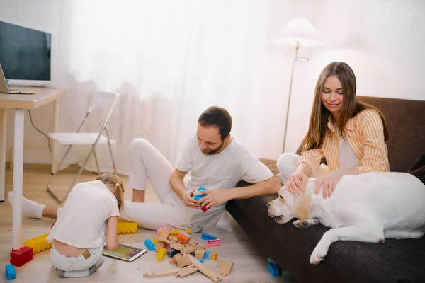 Crianças brincando juntas no chão, enquanto os pais jovens relaxando em casa — Fotografia de Stock