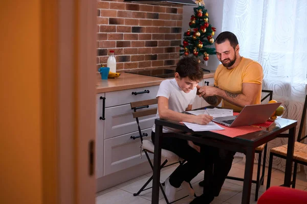 Pai cuidadoso com o filho fazendo lição de casa na cozinha — Fotografia de Stock