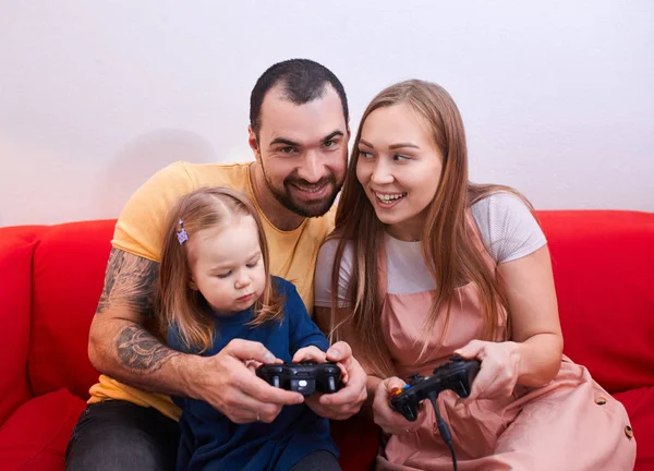 Padres encantadores y niña sentarse a jugar videojuegos — Foto de Stock