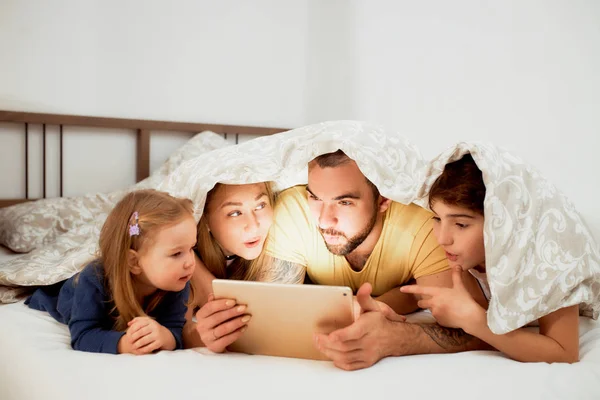 Família amigável emocional gosta de assistir filme na cama — Fotografia de Stock