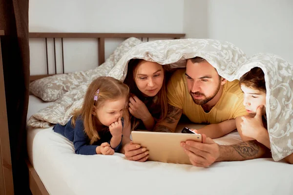 Mooie familie met kinderen op bed — Stockfoto