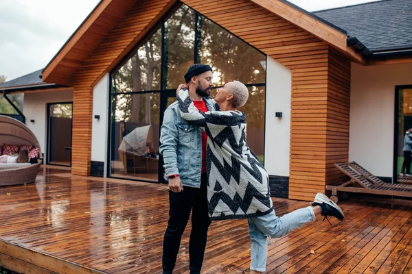 Casa, amor e conceito de férias. feliz casal stand beijos no fundo da casa de madeira — Fotografia de Stock