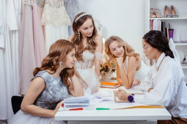 good-looking designer tailor of wedding dresses and young women