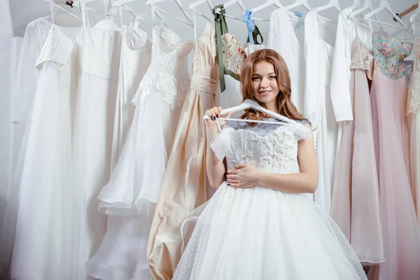 Jovem noiva feliz olhar para o vestido de casamento bonito — Fotografia de Stock