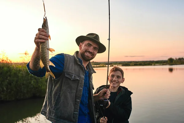 La prima pesca congiunta di padre adulto e figlio adolescente in giornata calda e soleggiata . — Foto Stock