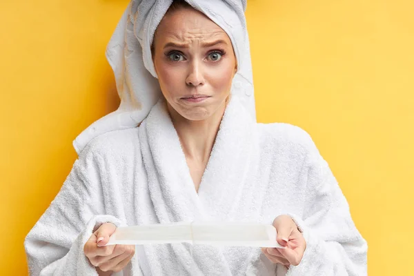 Primer plano de la mujer caucásica asustada sosteniendo tiras de cera para la depilación —  Fotos de Stock